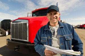 image of a caucasian male truck driver standing in front of a shiny red tractor against a blue sky with whispy clouds