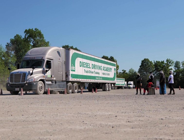 DDA semi truck parked in dirt training yard while a group of students stand nearby