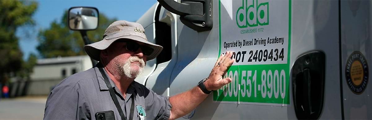 Image of veteran DDA trucking program veteran instructor resting hand on door of tractor