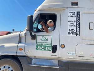Student leaning out window of DDA semi truck to look at front tire