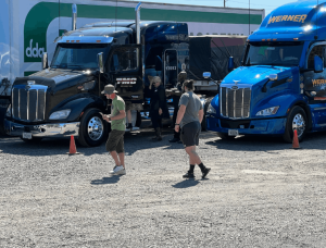 Two students walking in DDA training yard. TMC and Werner semi truck parked behind.