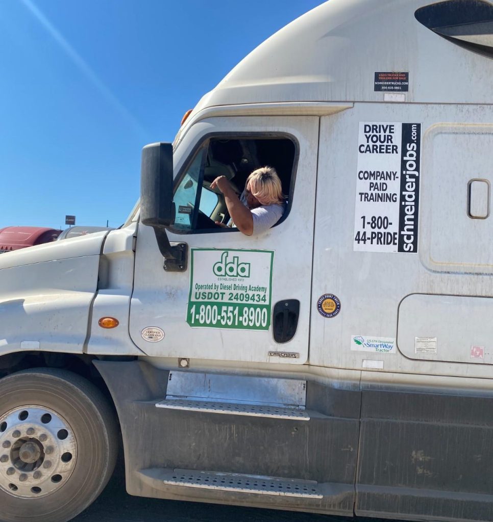 CDL student driving a DDA semi truck, looking at side mirror