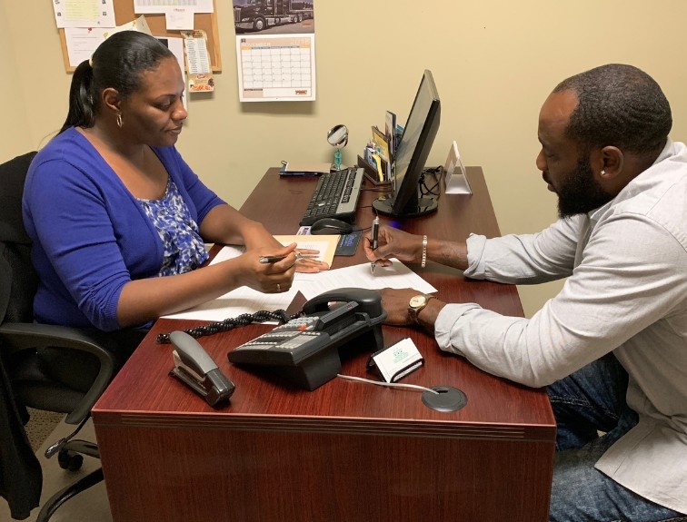 A prospective CDL student meets with a truck driving school admissions representative at a desk to discuss enrollment