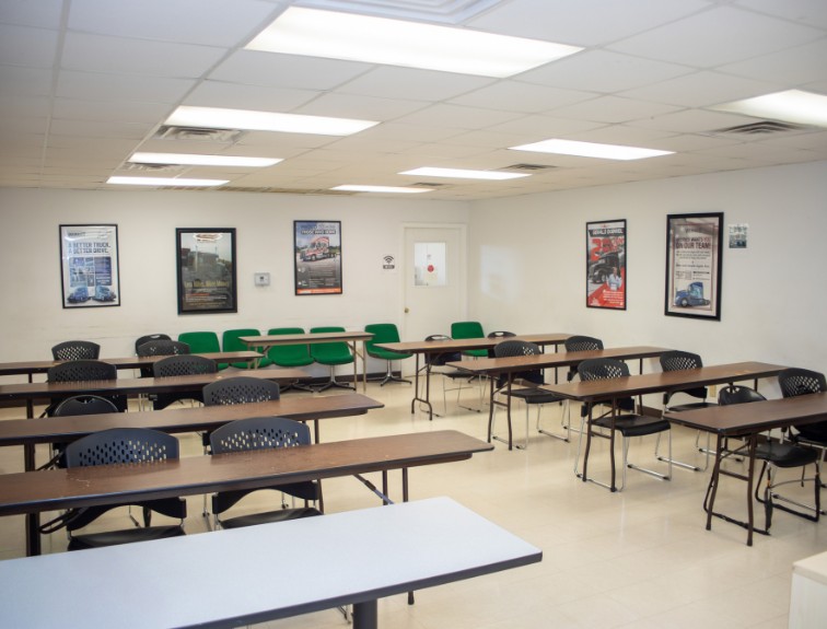 An empty DDA classroom with rows of tables and chairs, with trucking career posters on the walls.
