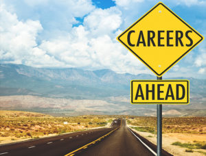 photo image of a yellow street sign that reads 'career ahead' against on the side of a wide open road with mountains in the background
