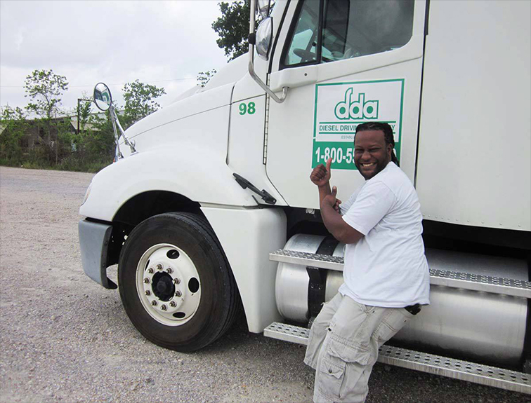photo of a male student standing in front of a DDA truck giving a thumbs up and smiling at the camera